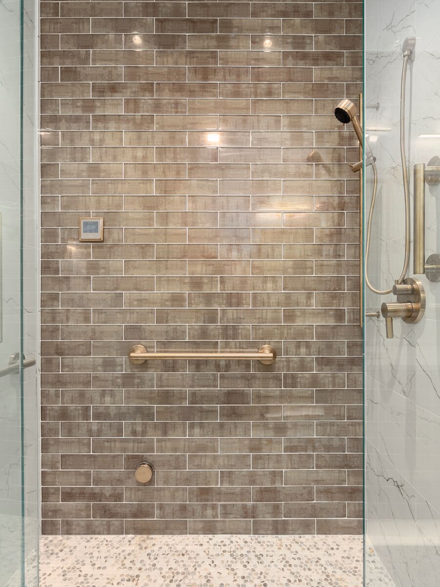 Walk-in glass shower with a tiled feature wall and brass fixtures